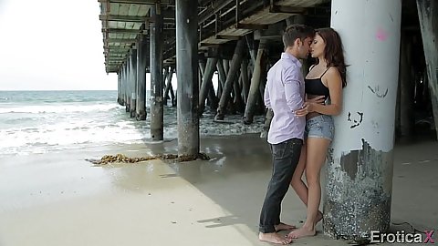 Making out fully clothed under a bridge on the beach