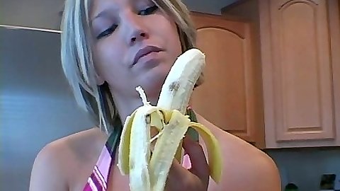 Blonde babe eating a banana in the kitchen
